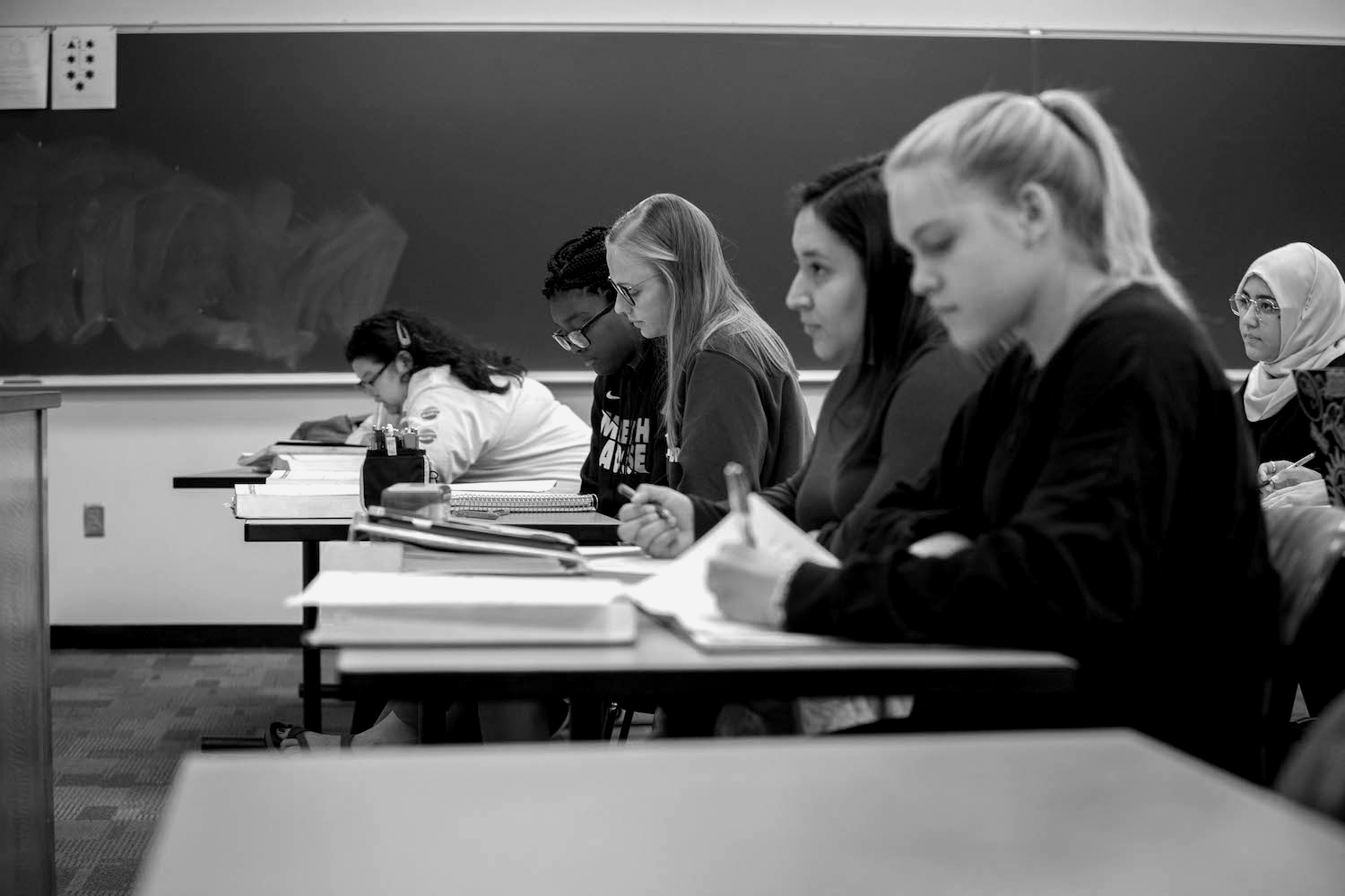 Female students pay attention in a math class and write down problems.