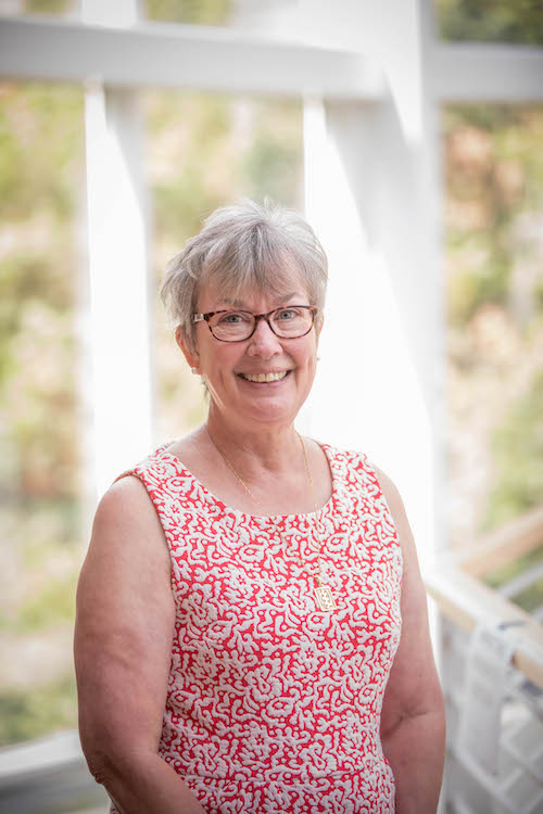 Julie Kolb smiling at the camera in a red and white patterned top.