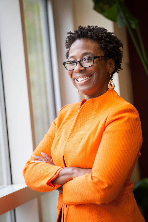 Tomecca Sloane smiling at the camera in an orange dress sweater.