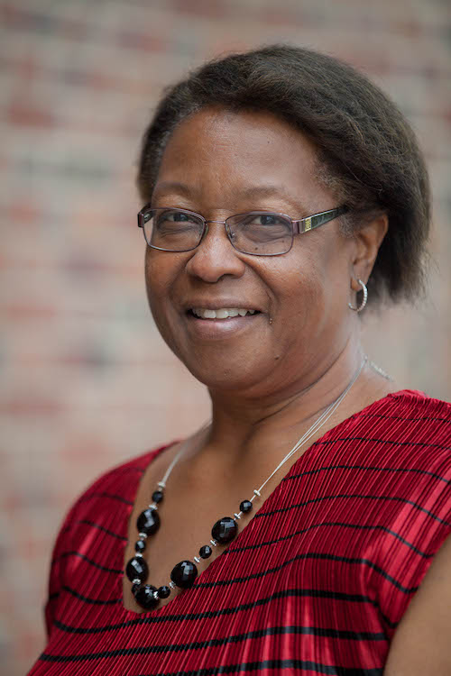 Walda Powell smiling at the camear in a red shirt with black stripes.